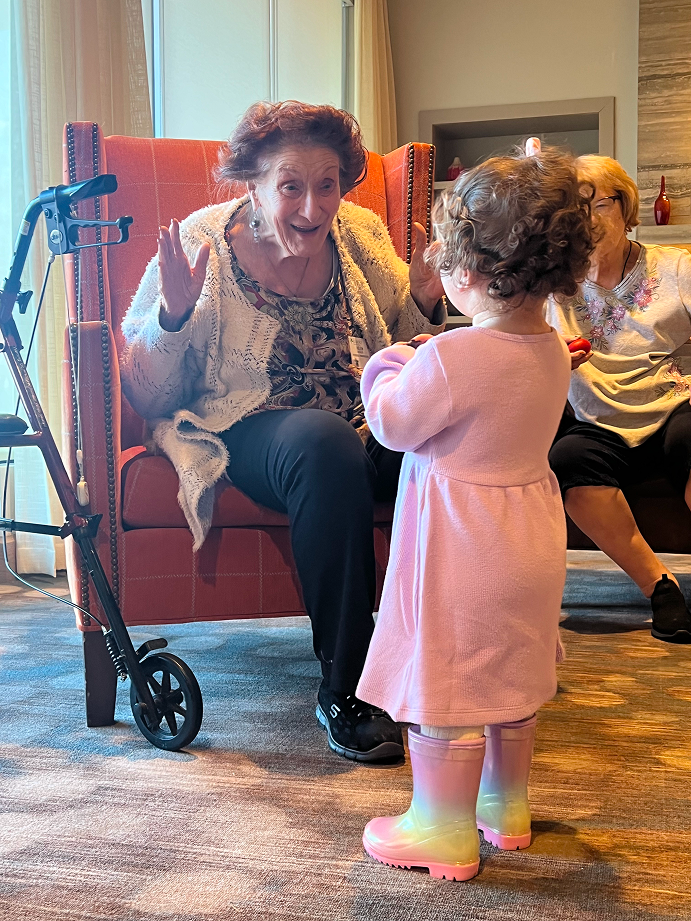 An elderly woman looking joyfully at a little child